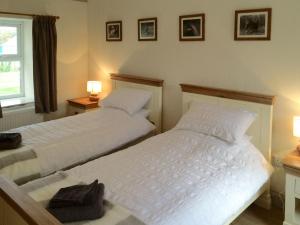WhitekirkCauldside West Cottage的卧室设有两张单人床和两盏灯。