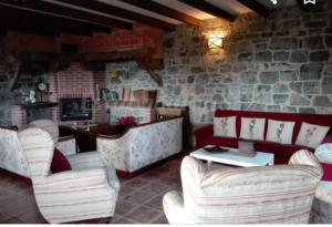 La Rectoral de Valdedios.Casa rural con chimenea的一间设有白色椅子和石墙的餐厅