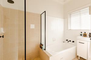 巴特曼斯贝海湾微风精品酒店的白色的浴室设有浴缸和淋浴。