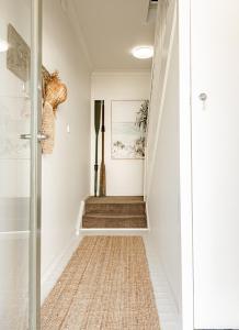 巴特曼斯贝海湾微风精品酒店的一条带白色墙壁的走廊和一条铺有地毯的楼梯