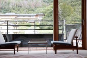松本Matsumoto Jujo的客房设有两把椅子、一张桌子和大窗户