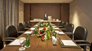 阿布扎比橡树利瓦行政套房酒店的一间会议室,里面摆放着长桌子和鲜花