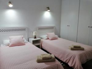 圣地亚哥海滩Casa Alisios的粉红色和白色的客房内的两张床