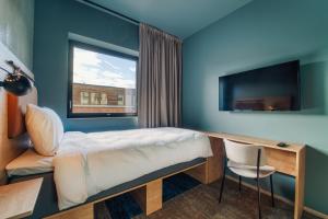 波多Smarthotel Bodø的客房设有床、书桌和窗户。
