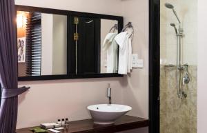 马累蜂巢酒店的浴室配有盥洗盆和带镜子的淋浴