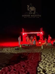 梅尔祖卡Sahara Majestic Luxury Camp的一群人晚上站在海滩上