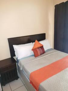 理查兹湾Mavundla guest house的一张带橙色和白色枕头的床