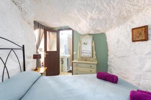 Lomo de AricoCasa Cueva Gaspara的卧室配有一张位于岩石墙内的床铺