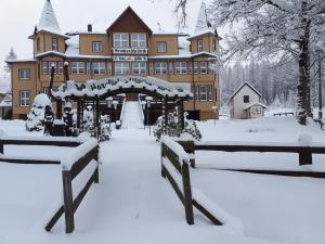 施尔奇Hotel Brockenscheideck的前面有长凳的大建筑,被雪覆盖