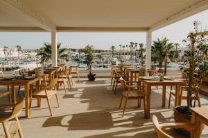 卡兰博希Lago Resort Menorca - Casas del Lago Adults Only的一间带木桌和椅子的餐厅以及一个码头