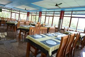 伊都基Laurel Heights Resort Idukki的用餐室设有桌椅和窗户。
