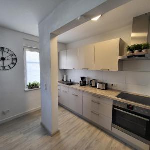 大雷申Ferienwohnung NR1的厨房配有白色橱柜和墙上的时钟