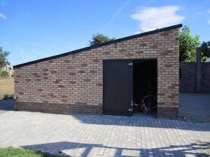 NeerpeltDe Hoog Velden 11的砖砌的建筑,里面装有自行车车库