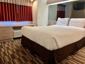 布卢明顿Microtel Inn & Suites by Wyndham Bloomington MSP Airport的一张大床,位于酒店房间,配有红色窗帘