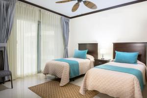 雅科Diamante del Sol Ocean front, Jaco Paradise CR的一间卧室配有两张床和吊扇