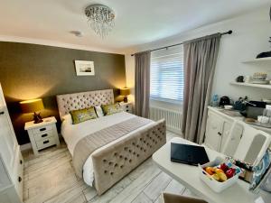 利明顿THE KNIGHTWOOD OAK a Luxury King Size En-Suite Space - LYMINGTON NEW FOREST with Totally Private Entrance - Key Box entry - Free Parking & Private Outdoor Seating Area - Town ,Shops , Pubs & Solent Way Walking Distance & Complimentary Breakfast Items的一间卧室配有一张床和一张带笔记本电脑的书桌