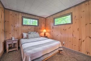 Comfy Burt Lake Abode - On-Site Lake Access!的一间卧室设有一张床和两个窗户。