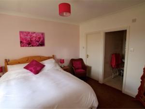 韦茅斯Jurassic Apartments的卧室配有带粉红色枕头的大型白色床