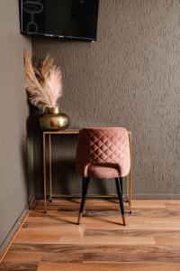 法尔肯堡Hotel La Casa的一张粉红色的椅子,坐在桌子旁,带花瓶