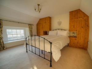 皮克林Kings Head Cottage的一间卧室设有一张床、木制橱柜和窗户。