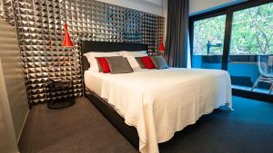 里斯本Hills Hotel Lisboa的一间卧室配有一张大床,配有白色床单和红色枕头
