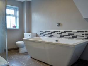 Newnham4 Greenhaye Cottages - Uk31236的带白色浴缸的浴室和卫生间
