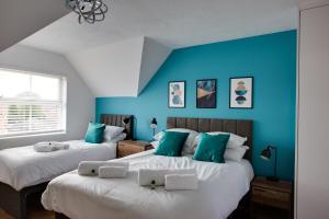 史云顿ST AUSTELL - Spacious Home, High Speed Wi-Fi, Free Parking, Garden的蓝色墙壁客房的两张床