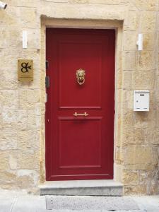 瓦莱塔Valletta Home -Dar il-Kavallier Jacques de Quiqueran的红色的门,上面有金狮