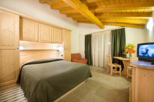马代西莫波士科内套房酒店的一间卧室配有一张床、一张书桌和一台电视