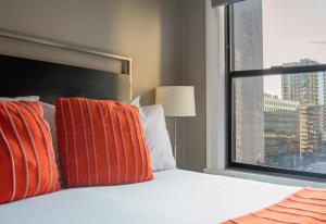 西雅图麦克斯酒店的一张带橙色和白色枕头的床和窗户