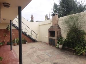 科尔多瓦Córdoba Alquila Alto Alberdi的建筑中带砖砌壁炉的户外庭院