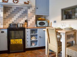 凯里堡Plum Cottage的厨房配有炉灶和带微波炉的桌子。