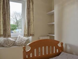 凯里堡Plum Cottage的一间卧室设有一张婴儿床和一扇窗户。