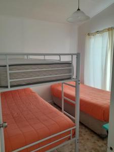 巴伊亚英格莱萨Cabanas bahia inglesa的一间卧室配有两张双层床,提供橙色床单
