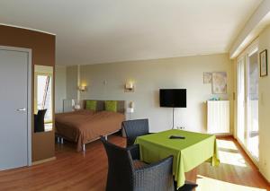 赫纲兰德贝尔韦代雷酒店的客房设有一张床和一张绿色的桌子和椅子。