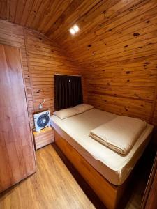 大叻The Hobbit Bungalow的一间小卧室,配有一张位于木制房间内的床