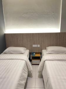 怡保Fresh Hotel的酒店客房设有两张床,中间设有床头柜。