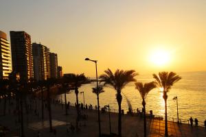 贝鲁特贝鲁特湾景酒店的日落时分拥有棕榈树和海洋的海滩