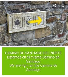 德巴Agroturismo Erlete Goikoa -ESTAMOS EN EL CAMINO DE SANTIAGO -WE ARE ON THE CAMINO DE SANTIAGO的黄色箭头石墙上的标志
