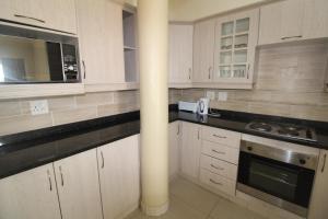 乌旺戈海滩Saints View Resort Unit 1的厨房配有白色橱柜和黑色台面