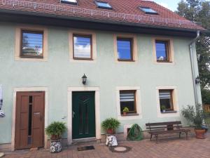 德累斯顿Ferienhaus -Am alten Dorfplatz-的绿色门和长凳的房子