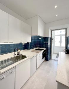 里斯本New Art Apartment的厨房配有白色橱柜和蓝色瓷砖