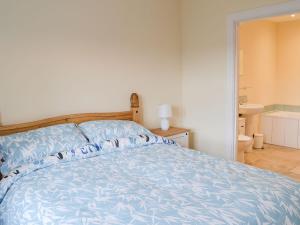 EdlinghamQuails Nest的一间卧室配有一张带蓝色棉被的床