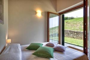 维罗纳皮纳托农家乐的一间卧室配有一张带绿色枕头的床和一扇窗户