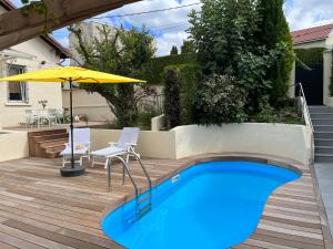 圣艾蒂安À la maison的后院的游泳池配有桌椅和遮阳伞