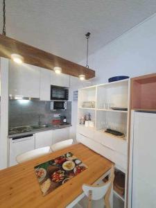 帕斯底拉卡萨SkiinSkiout Wifi Guardaesquís y Relax TETRAS的厨房配有木桌和白色橱柜。