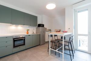 都灵Top Living Apartments - Carducci的厨房配有绿色橱柜和桌椅