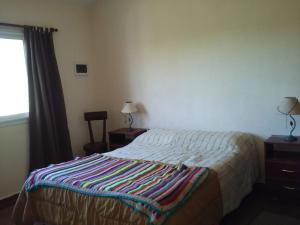 拉博尔萨Casa en Villa Los Aromos的一间卧室配有一张床,床上有条纹毯子