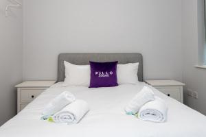 曼彻斯特Pillo Rooms Serviced Apartments - Trafford的一张带毛巾和紫色枕头的床