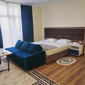 阿克套Rusel Hotel的一间卧室配有一张大床和一张蓝色的沙发